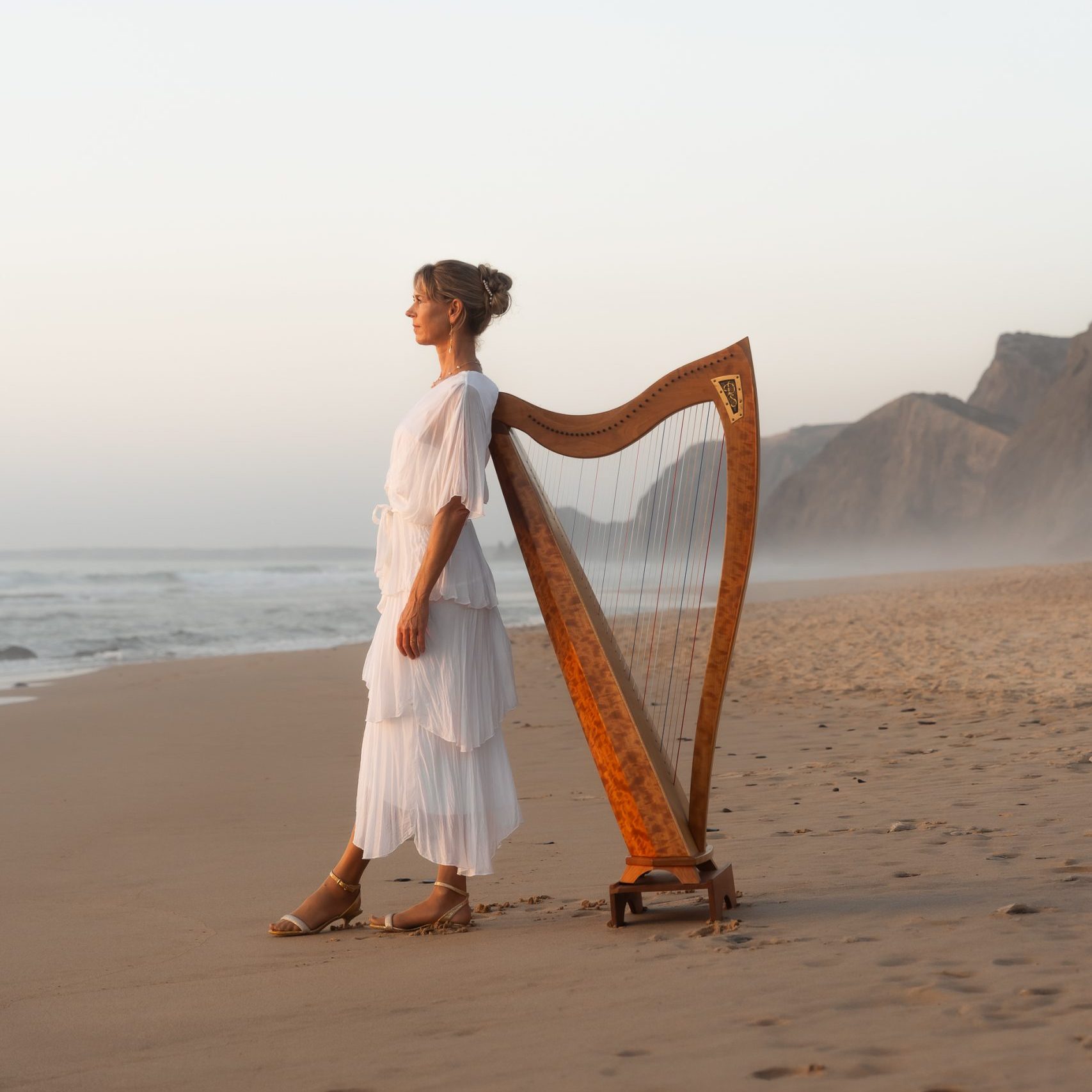 Danielle Riegel with her harp by the sea in Portugal