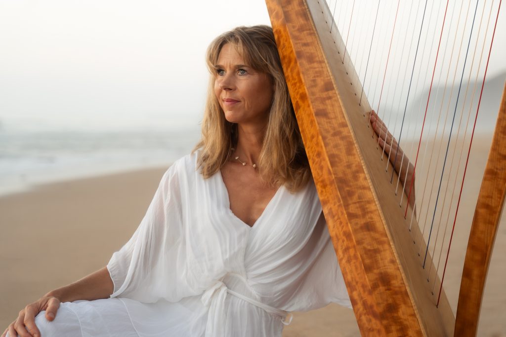 Portrait of Danielle Riegel with her harp by the ocean